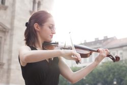 woman in black tank top playing violin during daytime