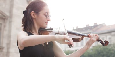 woman in black tank top playing violin during daytime